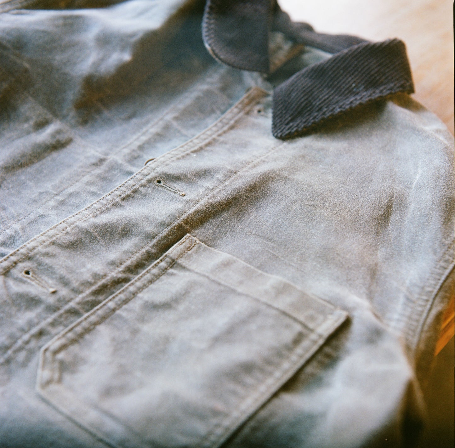 Close-up of a brown Muji chore coat with a corduroy collar after canvas waxing.