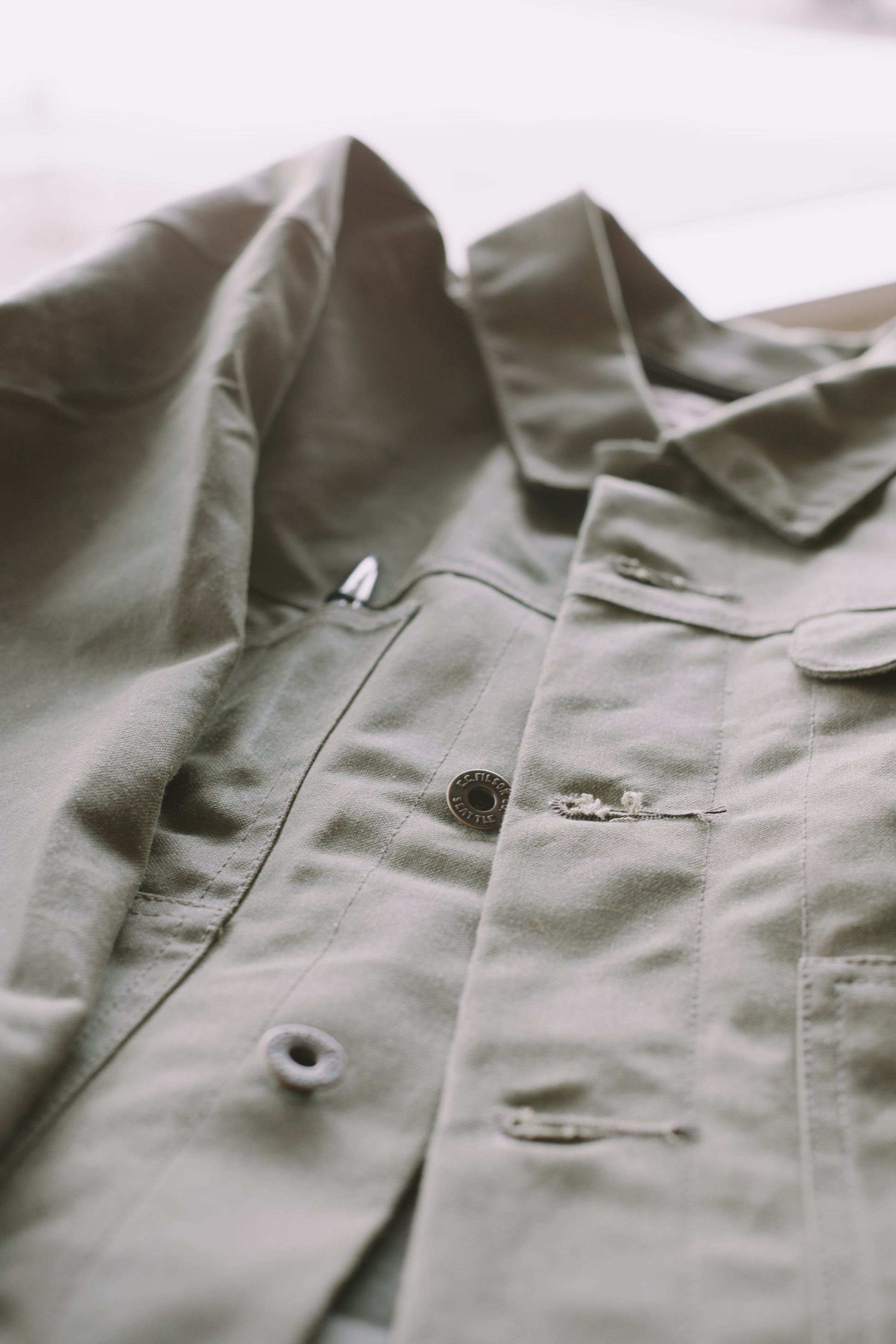 An image of a Filson SLC Short Lined Cruiser in military green .