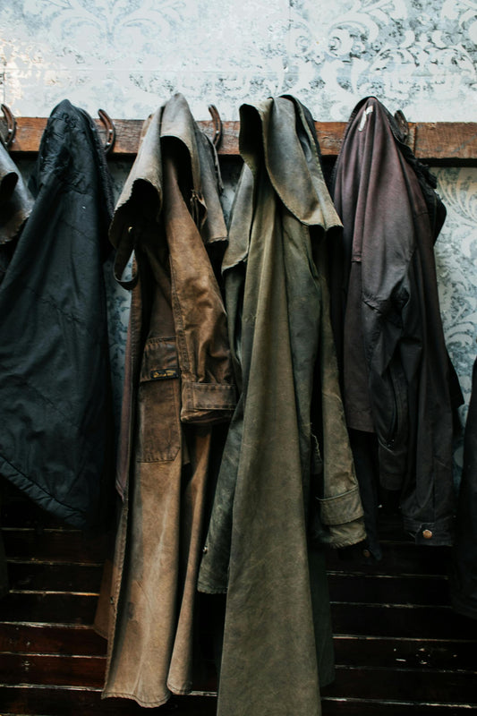 An image of short and long canvas jackets hanging up on a wooden rack.