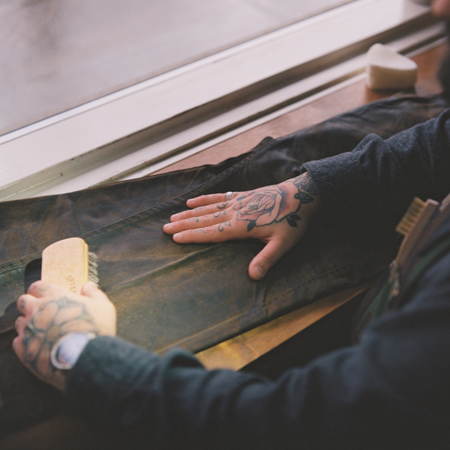 An image of a person cleaning a pair of waxed canvas pants.