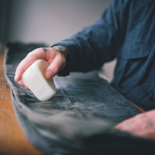 An image of a pair of Filson waxed canvas pants being waterproofed with natural wax.